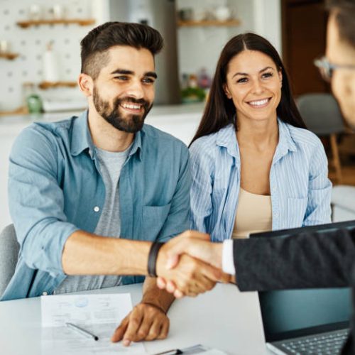 Real estate agent with couple shaking hands closing a deal